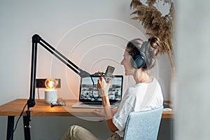 Woman working at home and talking into a microphone and recording podcast