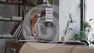 Woman working from home using laptop computer while reading text message. woman using laptop work study in office