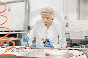 Woman working at ice cream factory conveyor