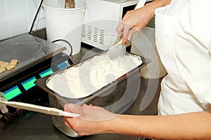 Woman working at ice cream factory is decorations of creamy vanilla and white chocolate ice cream.