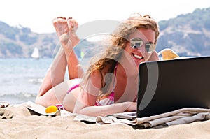 Woman is working on laptop on beach