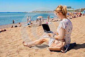 Woman working on laptop on the beach