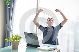 Woman working at laptop at big window with city view