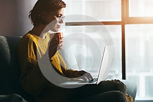 Woman working with laptop and coffee or tea at home quarantine