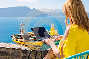 Woman working with laptop computer while having breakfast