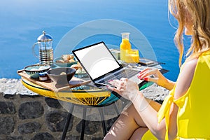 Woman working with laptop computer while having breakfast on terrace