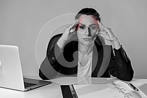 Woman working at laptop computer office desk in stress suffering intense headache and migraine