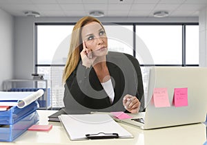 Woman working at laptop computer sitting on the desk absent minded and thoughtful sitting at business district office