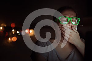 Woman working on laptop computer and yawning at night