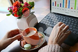 Woman working on a laptop and drinking coffee