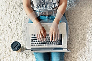 Woman working on a laptop. Female using a laptop sitting on floor, searching web, browsing information, having workplace at home.