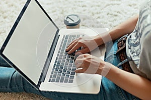 Woman working on a laptop. Female using a laptop sitting on floor, searching web, browsing information, having workplace at home.