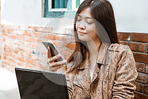 Woman working with laptop and her mobile phone