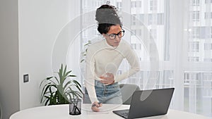 Woman working on laptop at home feels sudden menstrual abdomen pain gastritis.