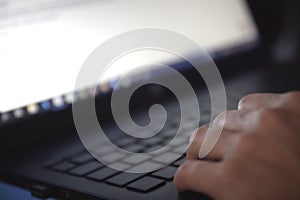 Woman working on laptop in home office hand on keyboard close up. in a dark environment