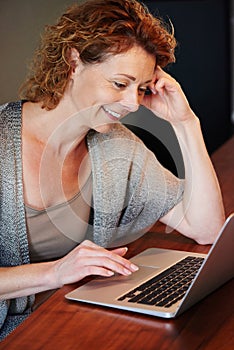 Woman working on laptop leaning on desk