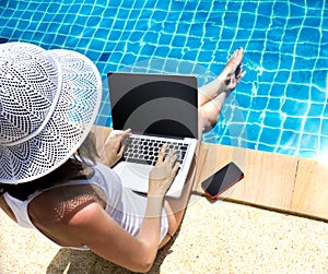 Woman working laptop near the poolside