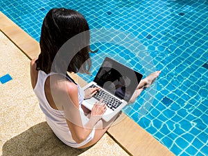 Woman working laptop near the poolside