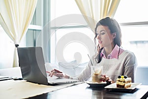 Woman working on laptop notebook computer at cafe, internet distance work, business lunch.