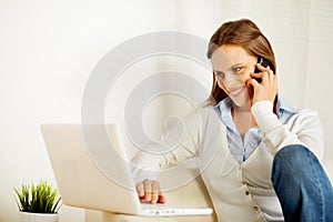 Woman working on laptop and on the phone