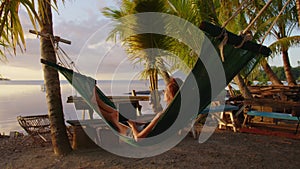 Woman working with laptop relaxing on hammock on the beach. concept of digital nomad, remote worker, independent