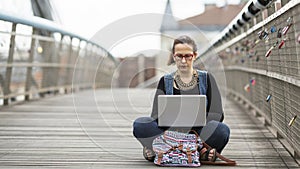 woman working on laptop while sitting on the street. The concept of working Freelancer or Blogger.