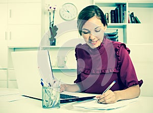 Woman working with laptop and taking notes