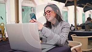 Woman working with laptop use smartphone sitting Street Cafe