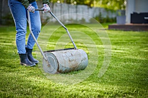 Woman working with lawn roller in the garden