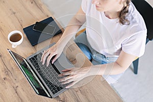 Woman working, learns, using laptop computer on table. Writing, typing. Blank screen, cell phone. Freelance concept. Work home