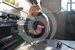 woman working in a modern factory and preparing materia for a CNC machine.