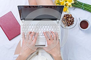 Woman working on a notebook in bed