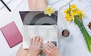 Woman working on a notebook in bed