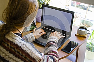 Woman working in office with digital tablet and notebook, writing and typing