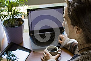 Woman working in office with digital tablet and notebook, writing and typing
