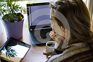 Woman working in office with digital tablet and notebook, writing and typing