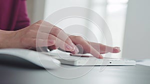 Woman is working in the office, typing text, clicking on the buttons