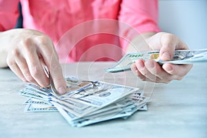 Woman working in ofice and counting usa dollars on table