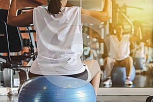 Woman working out with dumbbells sitting on gymnastic ball