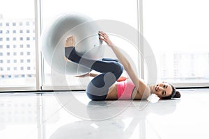 Woman working out with exercise ball in gym. Pilates woman doing exercises in the gym workout room with fitness ball. Fitness woma