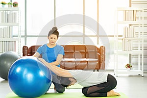 Woman working out with fitness ball of sportswomen practicing yoga. Stretching using fitness ball at home