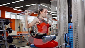 Woman working out in the gym. Athletic girl in the gym side view. A woman trains on a simulator.