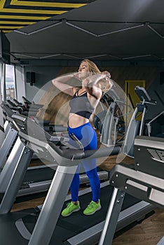 Woman working out at the gym. Girl with long hair runs on treadmill. Vertical frame