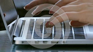 Woman working outdoor on laptop, hand on keyboard