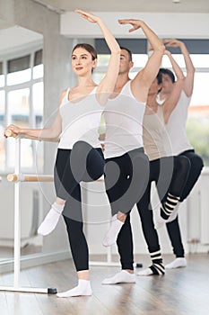 Woman working on Passe Developpe at barre at group ballet class photo