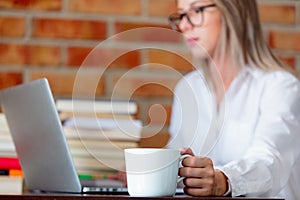 Woman on working place holding a cup of hot drink