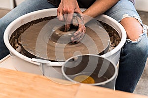 Woman working on a pottery wheel shaping the brown clay with both hands