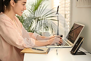 Woman working at table while mobile phone charging with wireless device