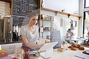 Woman working on the till at a coffee shop, wide angle photo