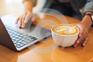 A woman working and touching on laptop computer touchpad while drinking coffee